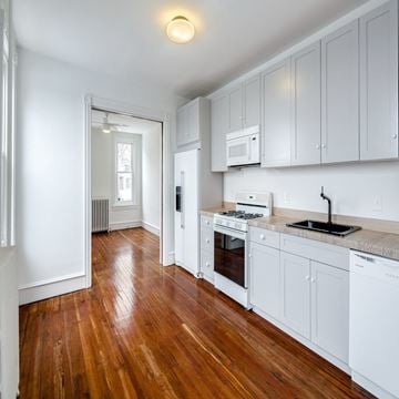 Philadelphia house for rent - A kitchen with white cabinets and a wooden floor.