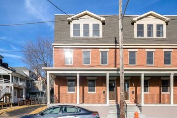 Philadelphia house for rent - A two-story brick house with a car parked in front.