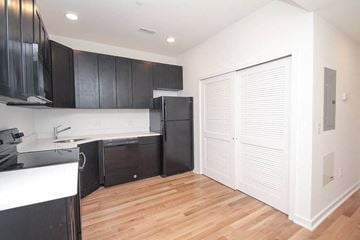 Philadelphia apartment for rent - an empty kitchen with black cabinets and a refrigerator