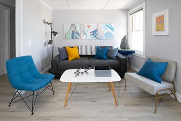 Newport apartment for rent - a living room with a gray couch and a white table and blue chairs