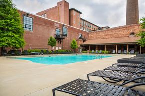 Greenville apartment for rent - A pool area with a brick building in the background.
