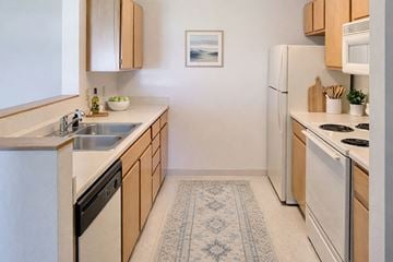 Mason City apartment for rent - A kitchen with a white refrigerator, a white stove, and wooden cabinets.