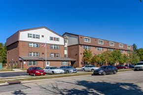 Miamisburg apartment for rent - a large brick building with cars parked in a parking lot