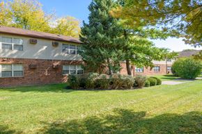 Piqua apartment for rent - exterior view of a brick apartment building with grass and trees