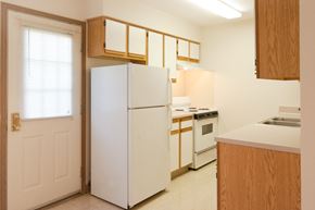 Lima apartment for rent - a kitchen with white appliances and wooden cabinets and a white door