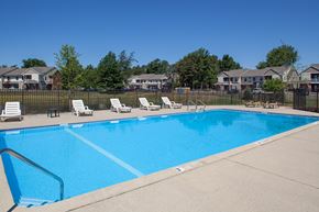 Holland apartment for rent - a swimming pool with chairs and a fence with houses in the background