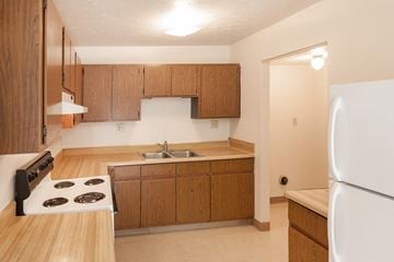 Fostoria apartment for rent - a kitchen with wooden cabinets and a stove and a sink