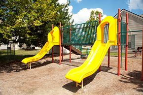 Dayton apartment for rent - a playground with two yellow slides and a green fence