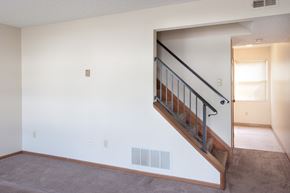 Cambridge apartment for rent - a living room with a staircase and a white wall and a door to a hallway