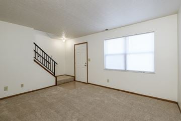 Logansport apartment for rent - the living room and entryway of a small house with a large window and carpet
