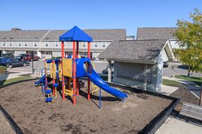 Columbus apartment for rent - a playground with a blue and red swing set in front of a building