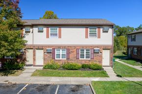 Columbus apartment for rent - a brick house with white siding and pink shutters and a lawn