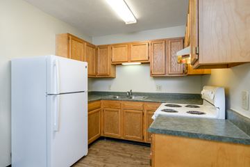 Dayton apartment for rent - a kitchen with wooden cabinets and a white refrigerator