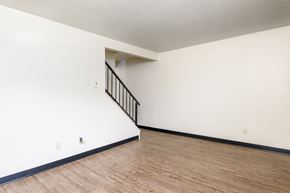 Dayton apartment for rent - an empty living room with white walls and wood flooring and a staircase