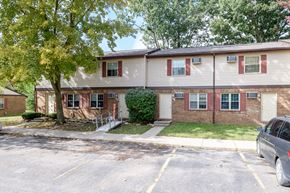 Urbana apartment for rent - front view of a white house with red shutters and a tree