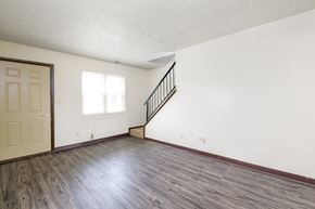 Moraine apartment for rent - an empty living room with white walls and wood floors and a door