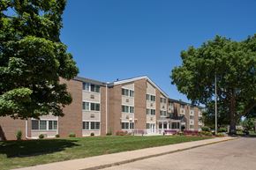 Peoria apartment for rent - a large brick apartment building with a lawn and trees