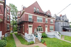Cincinnati apartment for rent - the front of a brick house with a yard and a white fence
