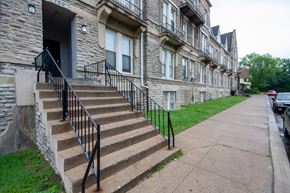 Cincinnati apartment for rent - a set of stairs in front of a stone building with black railings
