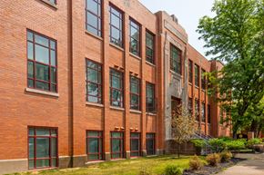 Covington apartment for rent - a large brick building with green windows and a sidewalk