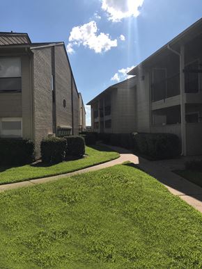 Houston apartment for rent - an apartment building with green grass and a blue sky