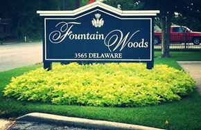 Beaumont apartment for rent - a sign for fountain woods with yellow flowers under it