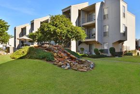 Beaumont apartment for rent - a rock formation in the grass in front of an apartment building