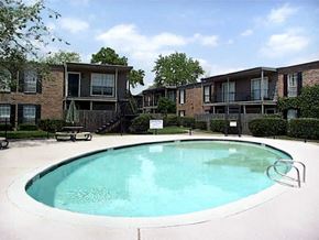 Houston apartment for rent - an oval swimming pool in front of an apartment building
