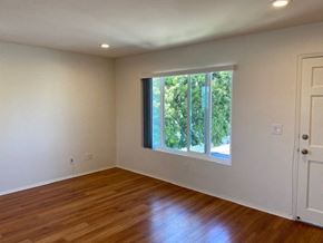 San Diego apartment for rent - an empty living room with a large window and wooden floors