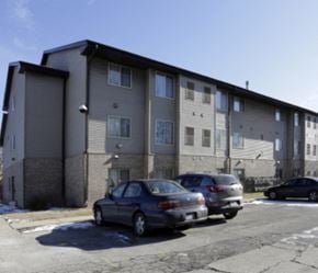 Milwaukee apartment for rent - A grey apartment building with cars parked in front.