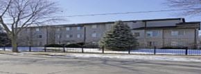 Milwaukee apartment for rent - A large building with a fence and a tree in front of it.