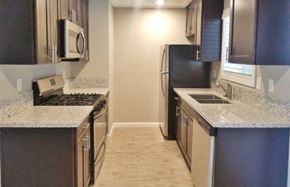 Manteca apartment for rent - View of kitchen with stone counters, stainless appliances, brown cabinets, and wood look flooring