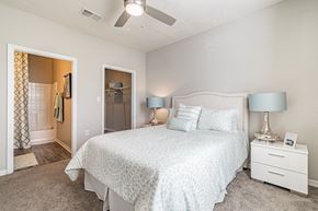 Brandon apartment for rent - One BR Apartments in Brandon FL - 2211 Grand Isle - Bedroom with Carpeted Floor, with White Nightstands, Lamps, Bed, Ceiling Fan, View of Attached Bathroom, and Large Closet with Storage Rack
