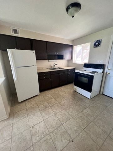 Columbus apartment for rent - A kitchen with a white refrigerator and black cabinets.